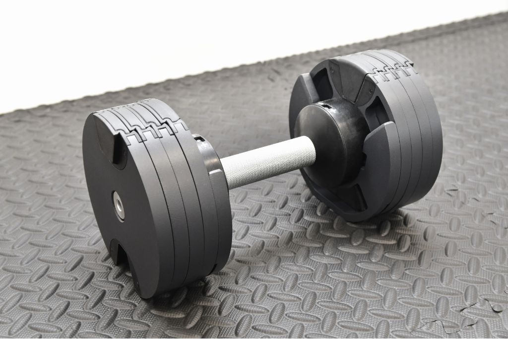 A pair of adjustable dumbbells on a workout mat, showcasing their compact design and weight selection mechanism. What adjustable dumbbells are best for home strength training?