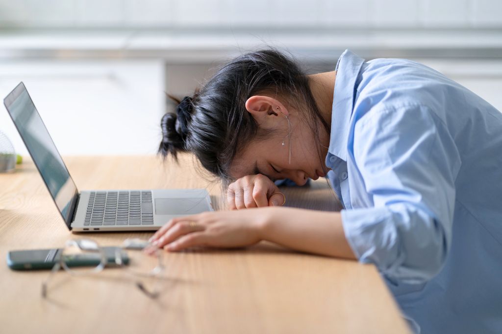 How burnout feels: woman collapsed on desk from exhaustion and overwhelm