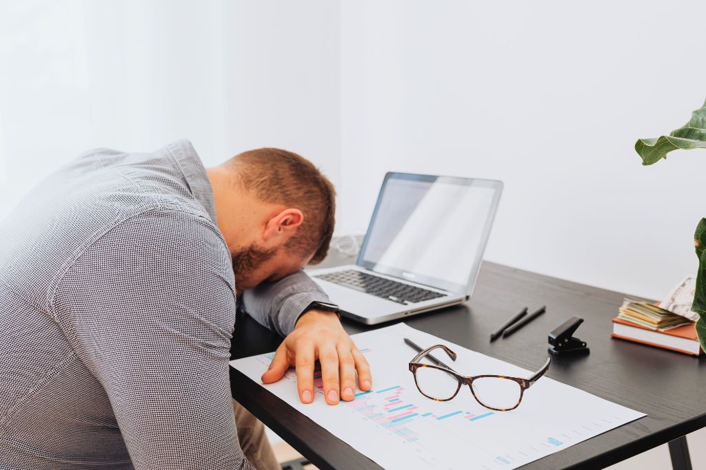 When burnout happens: man slumped over desk after mental and physical exhaustion at work