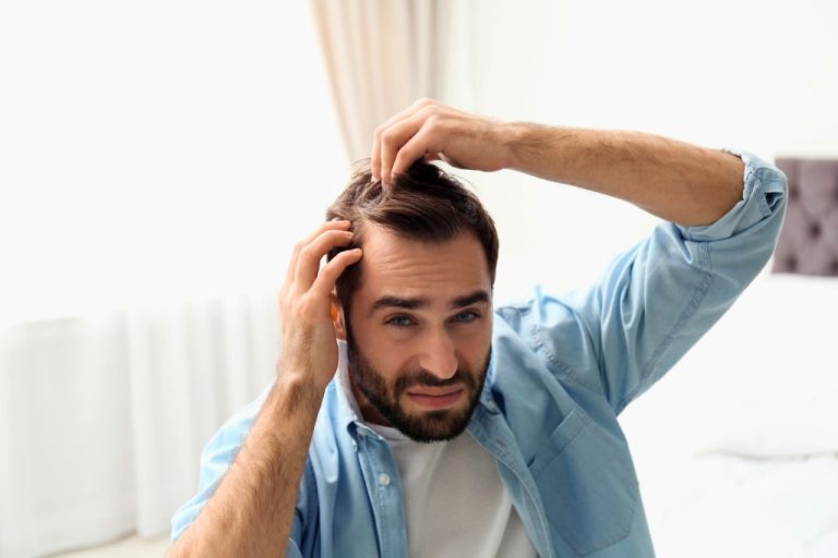 Man experiencing stress with hands in his hair, showing why hair loss happens due to internal imbalances.